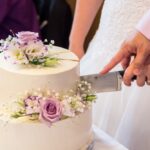 Cutting,A,Wedding,Cake,Decorated,With,Flowers